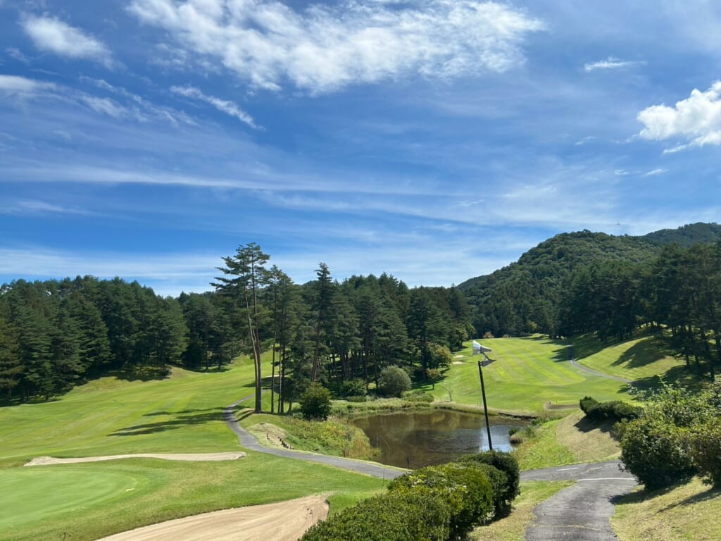 池とフェアウェイが広がるゴルフ場のコース風景
